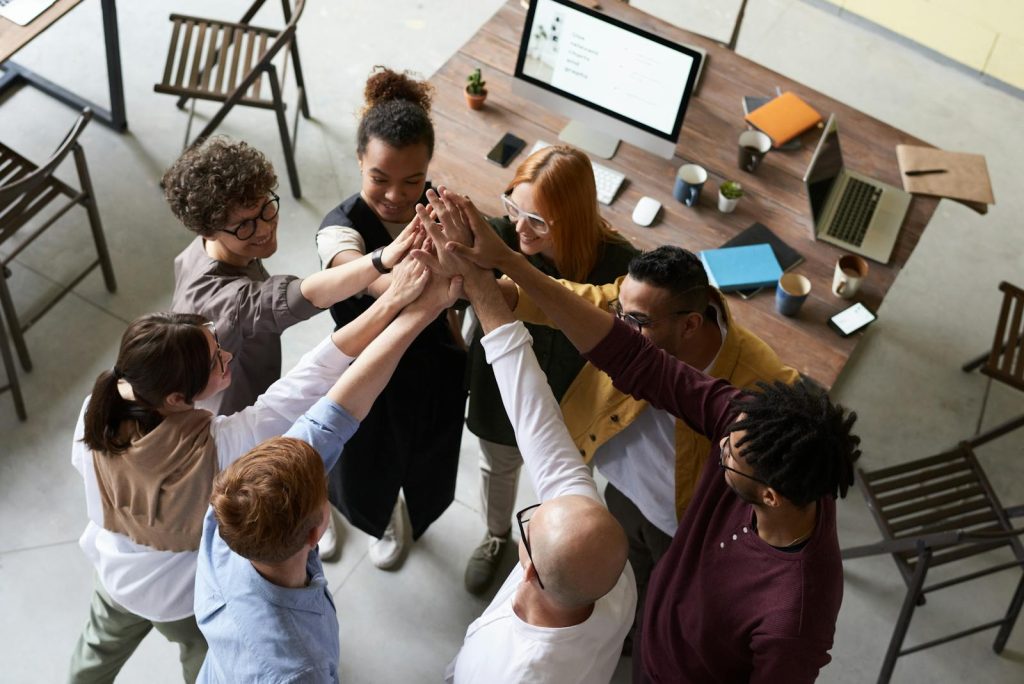 Un groupe diversifié de collègues se congratulant lors d'une réunion d'entreprise à l'intérieur.