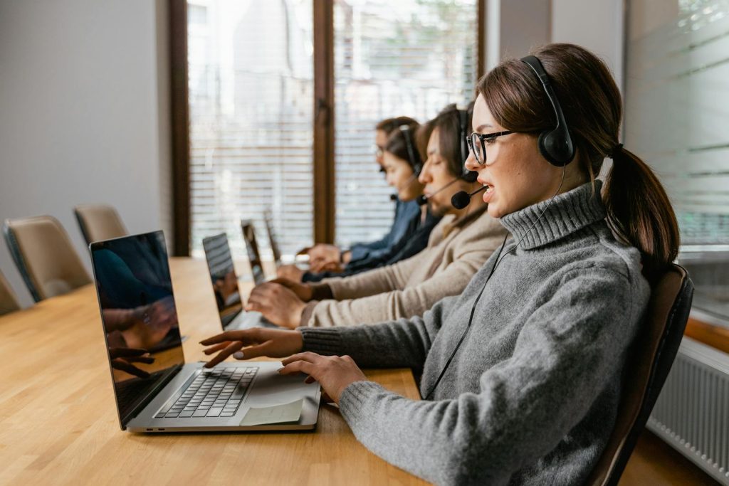 Équipe professionnelle de service à la clientèle travaillant dans un bureau moderne avec des écouteurs et des ordinateurs portables.