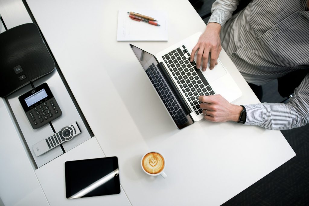 personne utilisant un ordinateur portable sur une table en bois blanc