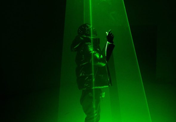 man in black jacket and pants holding green light
