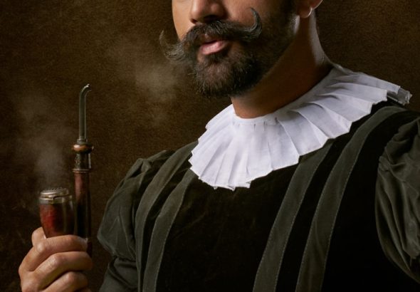 man wearing traditional clothes and holding smoking pipe